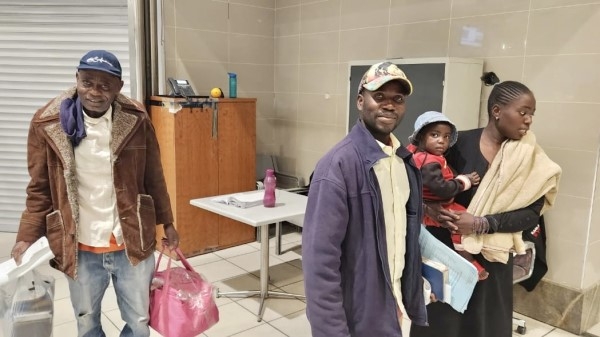 A family - older man, younger couple, and child - at an airport with baggage