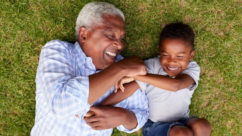 Man and boy lying on grass, laughing together