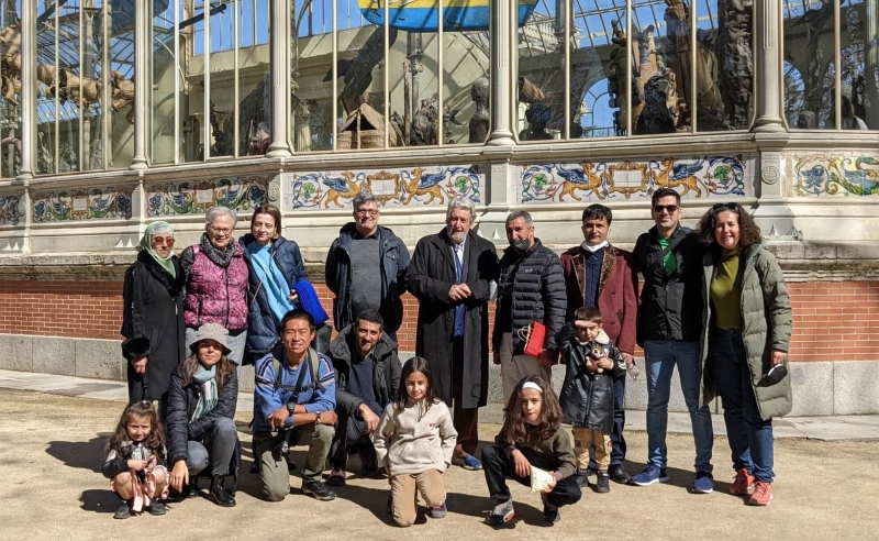 A group photo of people of different ages standing outside what looks to be a museum