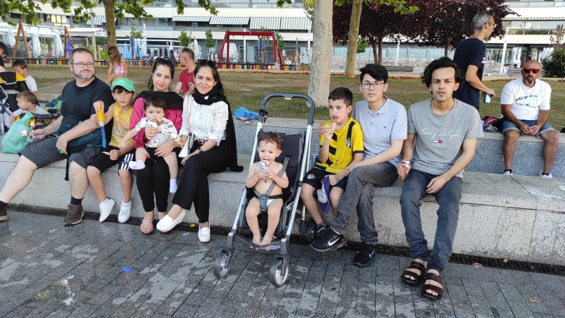 A group photo of people sitting on a wall eating ice cream - all different ages