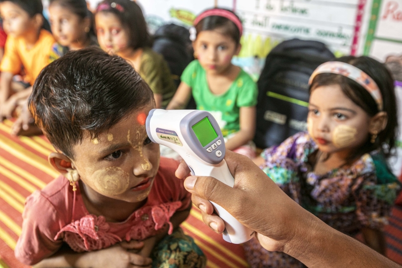 A young child gets their temperature taken