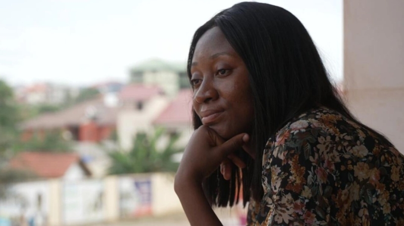 A photo of Louange Koffi - she is resting her chin on one hand, gazing off to the side, looking thoughtful