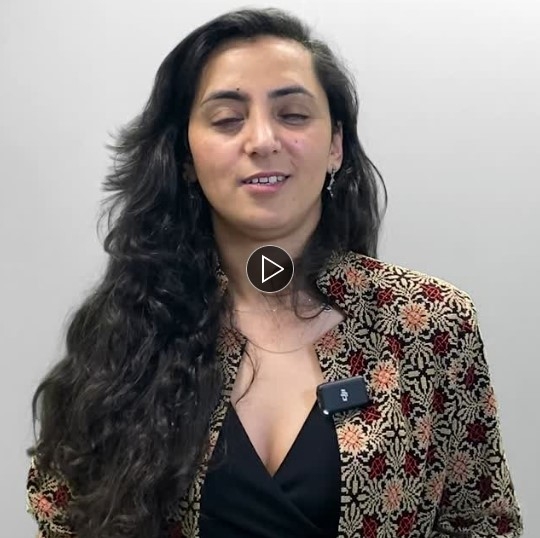 Khalida Popal standing with a white background behind them, facing the camera