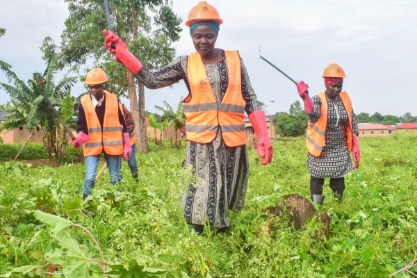 Three people in a field wearing high-visibility vests and hard hats