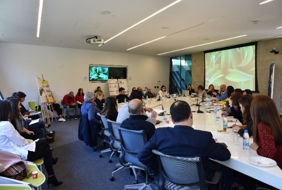 People at a conference room, seating on chairs around a table.