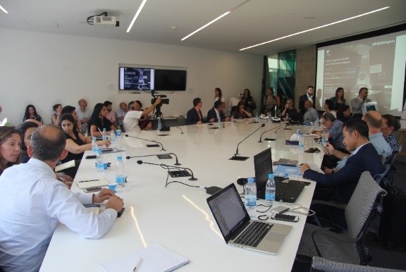 People at a conference room, seating on chairs around a table.