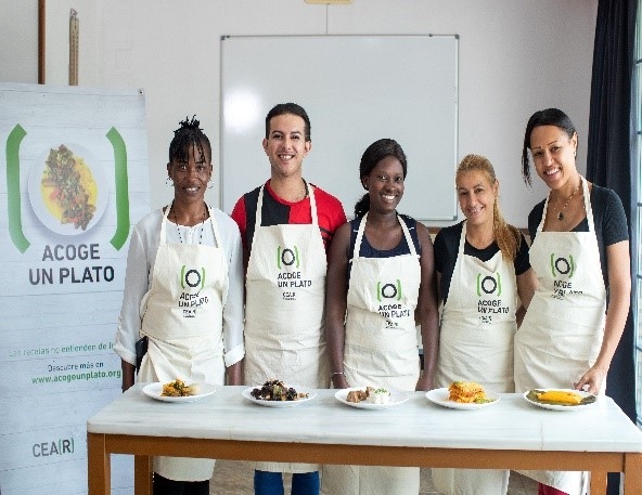 Women standing behind a table with food.