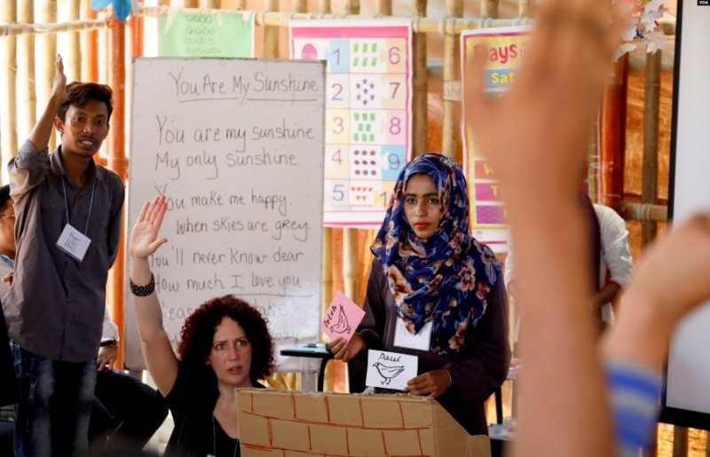 Women in a classroom raising their hands.