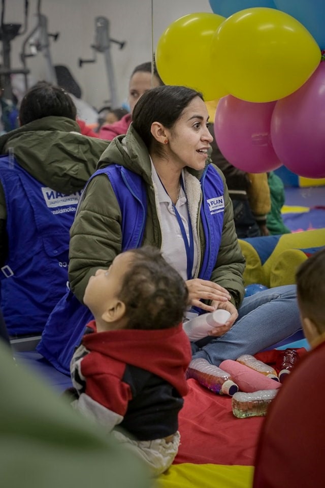 Woman providing support to children while seating in the ground.