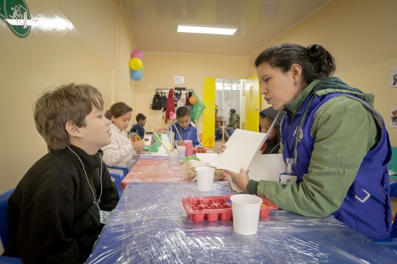 Child and woman interacting while seated at a table.