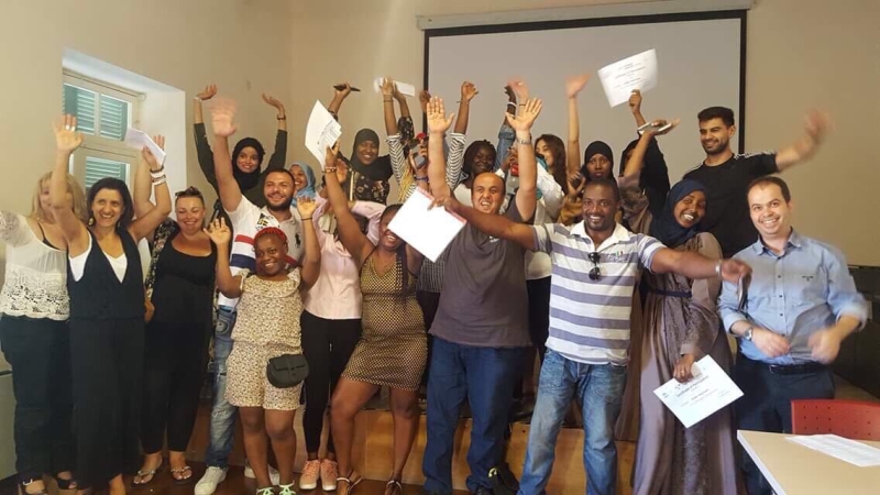 People standing in a room with their hands up holding certificates.