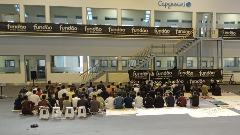 Men are sitting back to the camera in a makeshift mosque