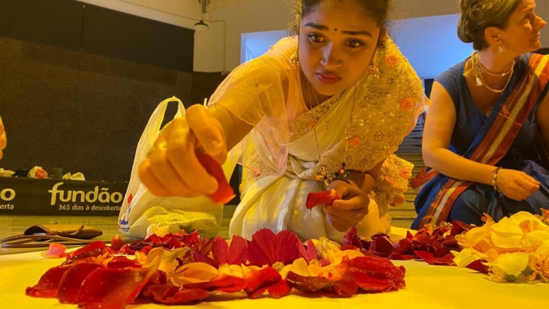 A girl in a sari is positioning flowers on the floor