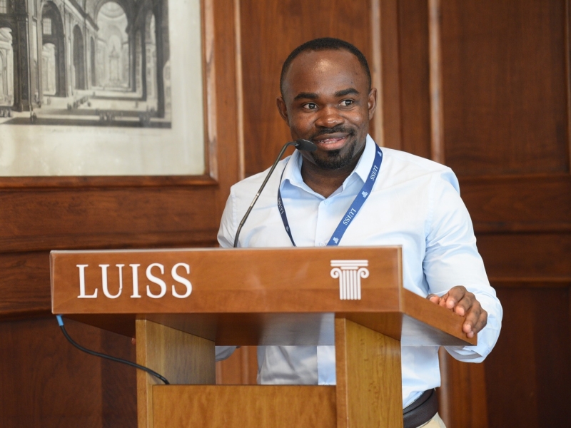 Bahati speaks at a lectern branded "LUISS"