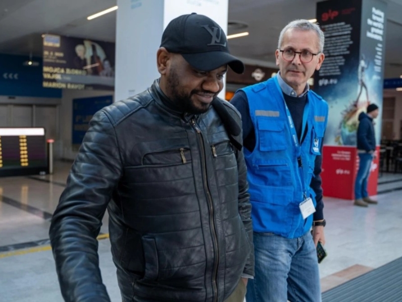 Two men walking together in the arrivals area of an airport.