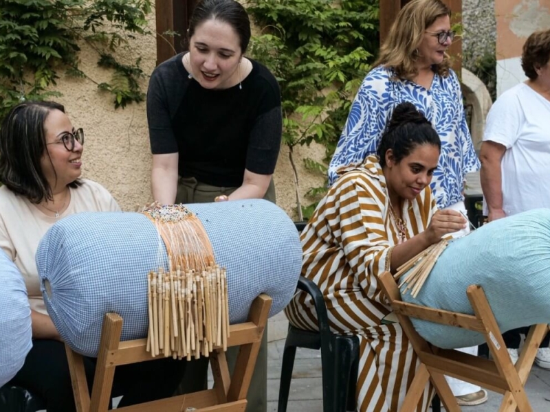 Women making lace demonstrate their craft to onlookers