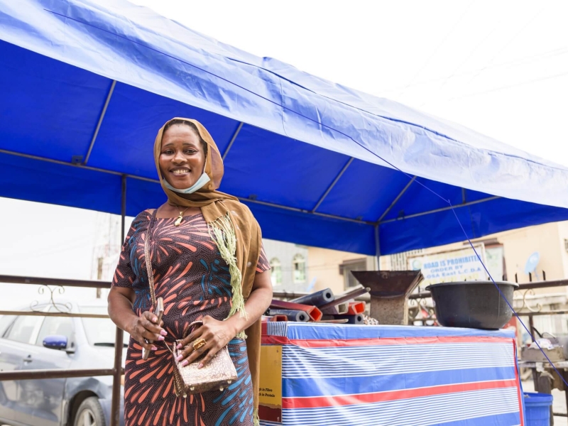 Diomade Manman, an urban refugee from Côte d’Ivoire, stands in front of her street food stall in Ajah market, Lagos state.