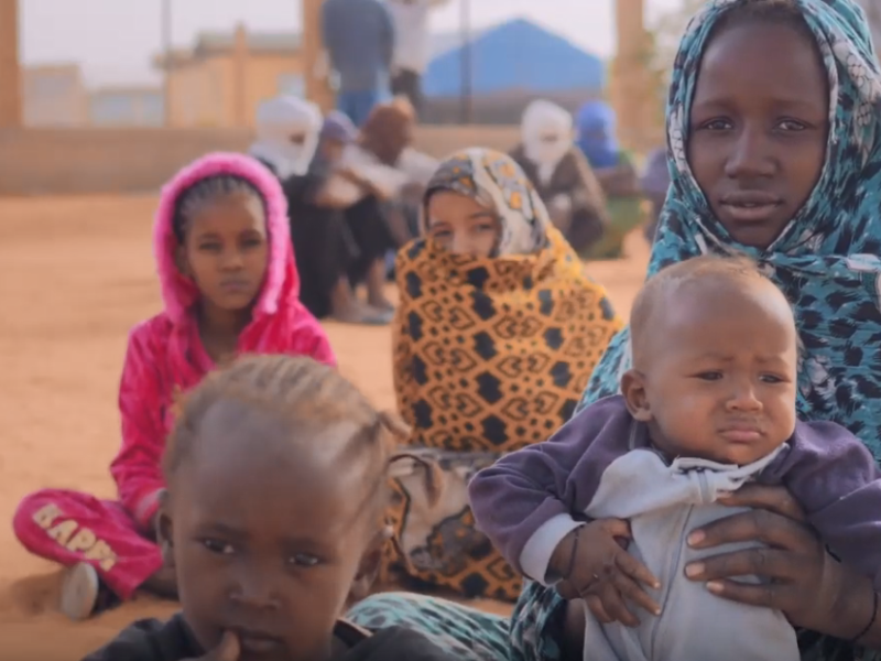 A woman and children seating in the ground.