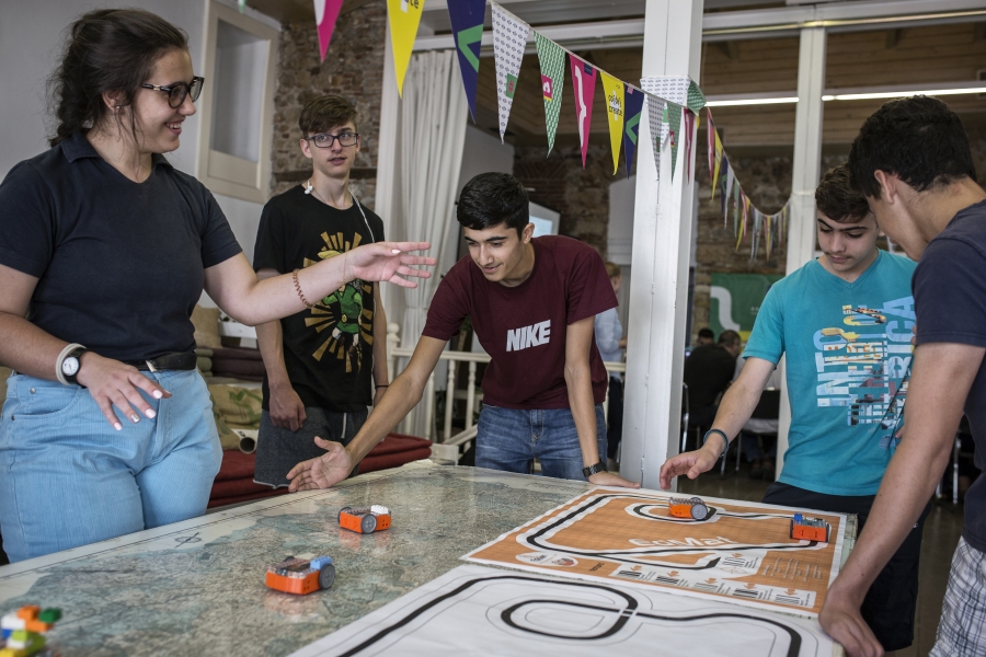 A group of youths working together to makes toy cars move.