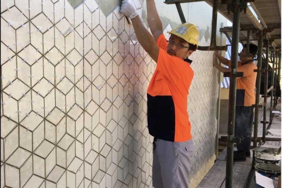 Man placing a tile in wall.