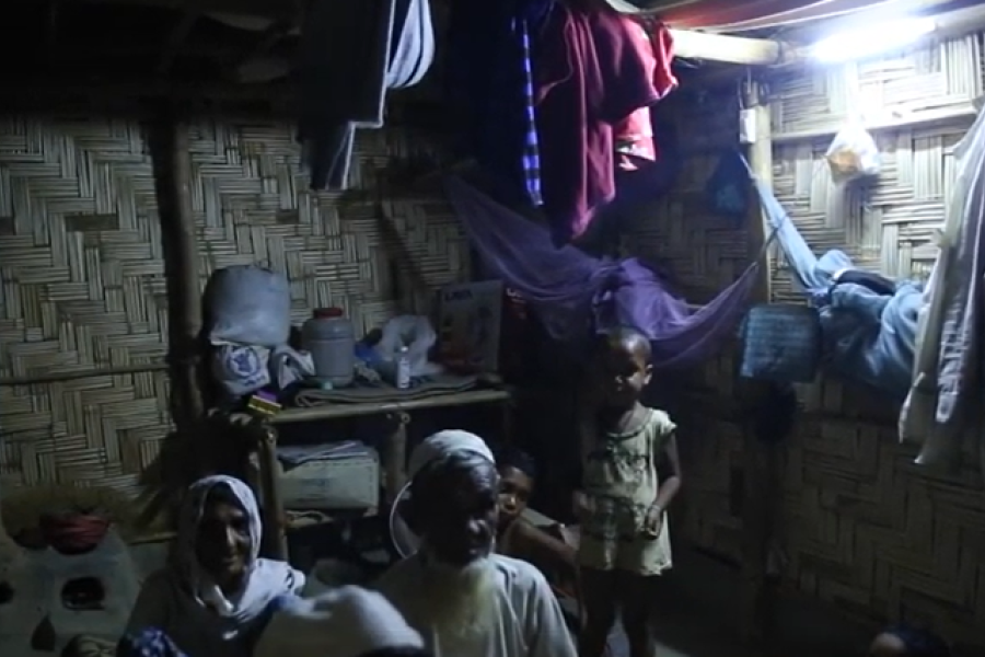 Family at a household in a camp setting, with light turned on.