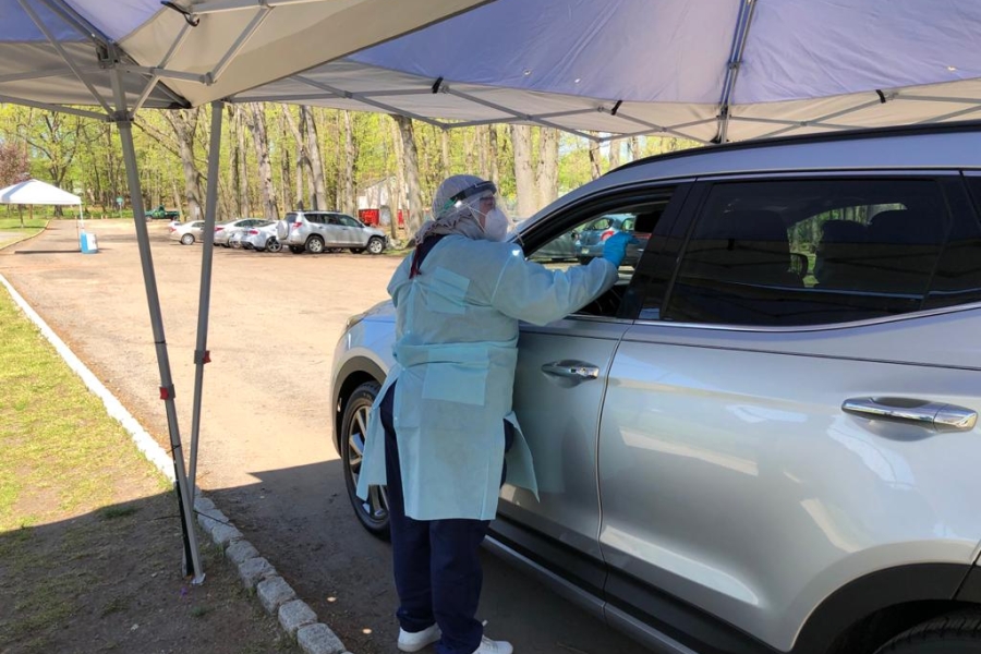 Iraqi refugee helps at a drive-thru coronavirus testing centre
