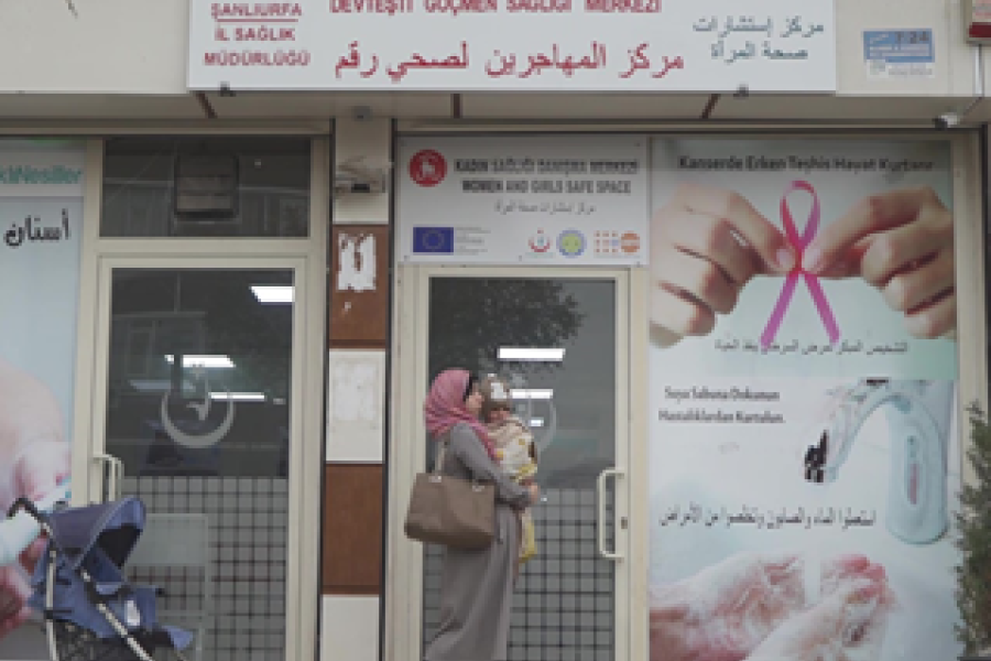 Woman walking past a Sexual and reproductive health centre with a baby.