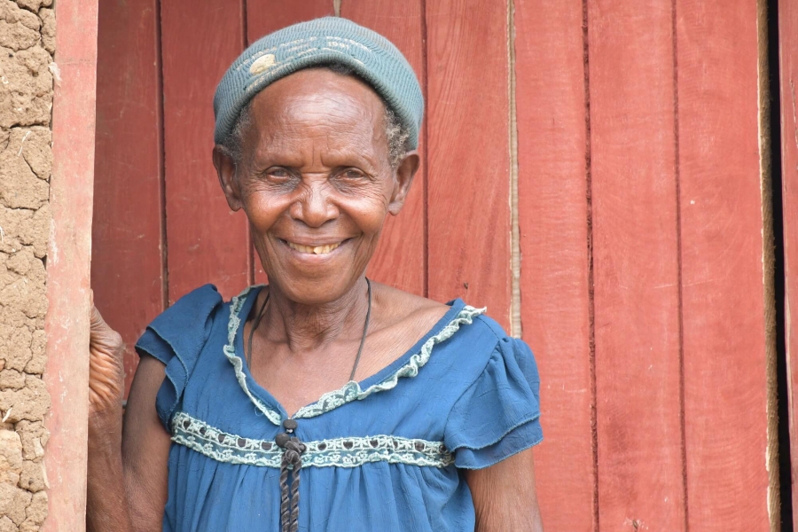 Soverinah Nyirazirahaga, a Congolese refugee in Uganda, stands in a doorway, smiling at the camera