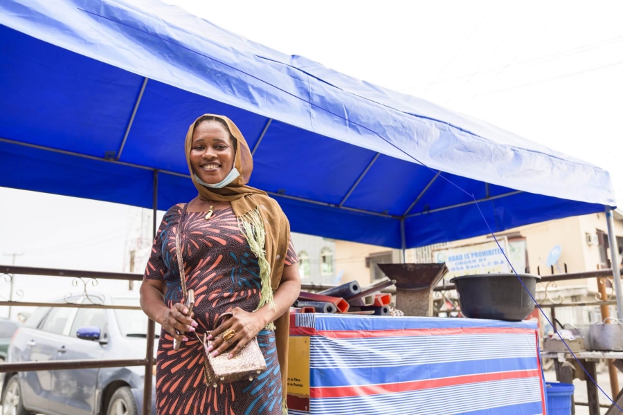 Diomade Manman, an urban refugee from Côte d’Ivoire, stands in front of her street food stall in Ajah market, Lagos state.