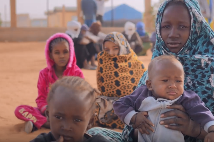 A woman and children seating in the ground.
