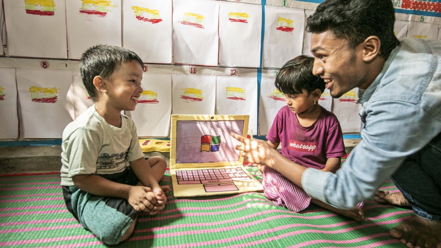 A man sits with two children with a fake laptop