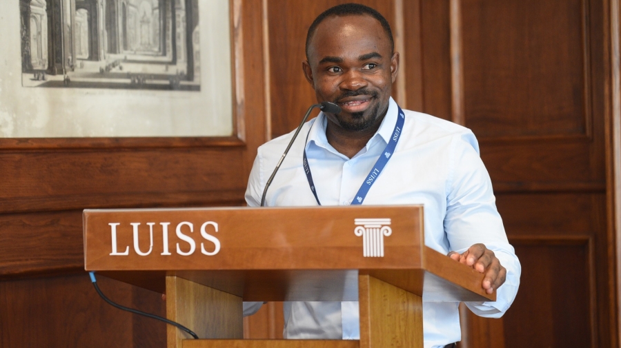 Bahati speaks at a lectern branded "LUISS"