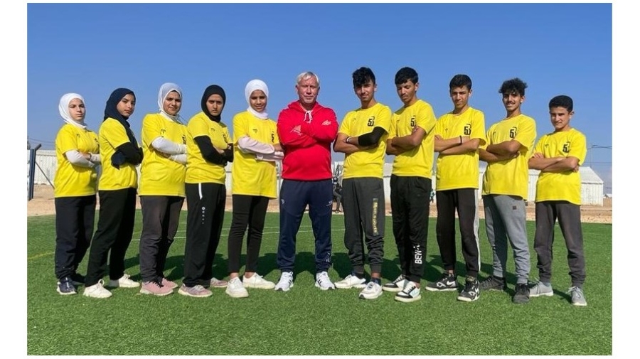 Group photo showing youths in sports clothes standing in a row, their arms folded.