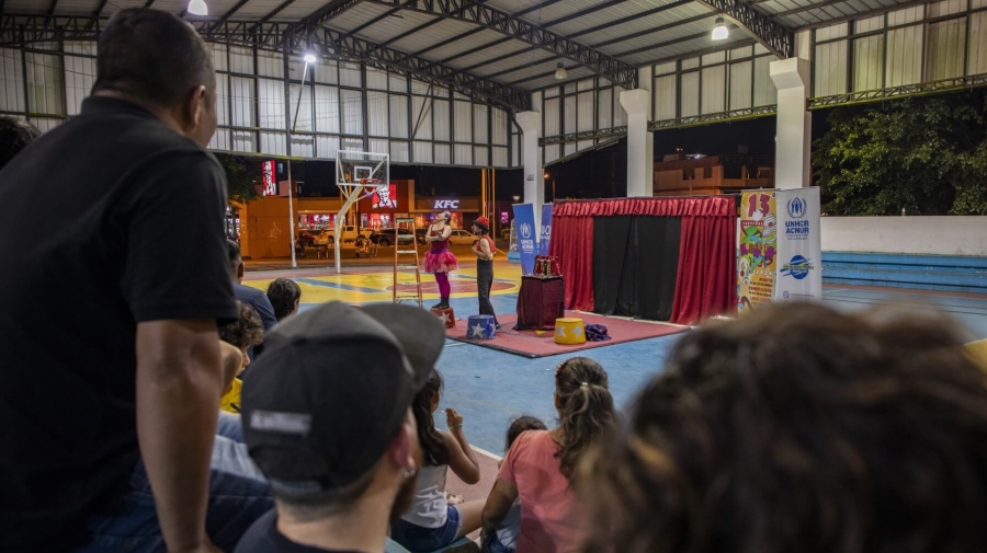 Two clowns performing in the middle of a sports hall with the audience in the foreground