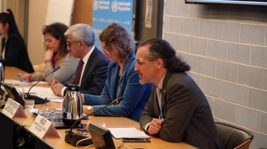 A photo of the panel, with four people sitting in a row - the closest one is speaking into a microphone