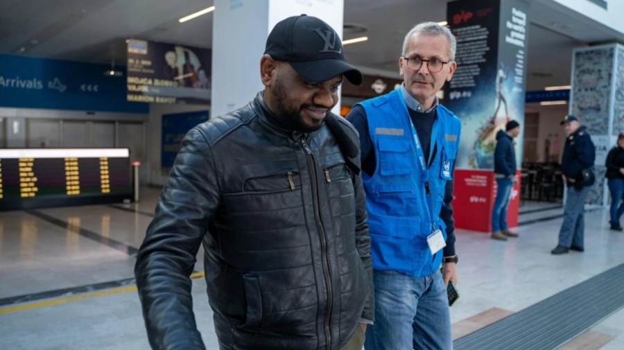 Two men walking together in the arrivals area of an airport.
