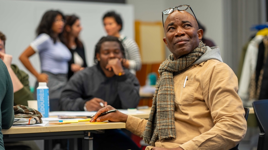 People sitting at a desk, a man holding a pen looks up